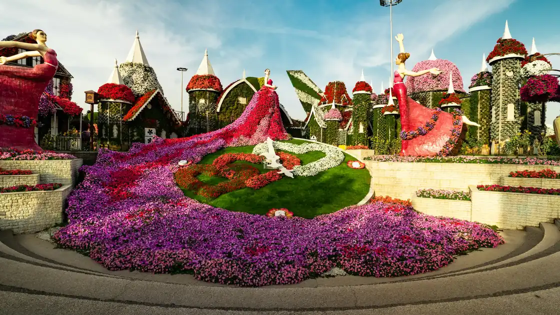 A small house covered in flowers in a flower park under a blue sky