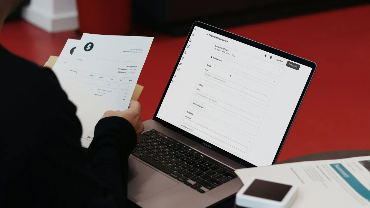 Laptop and paper invoices on a desk