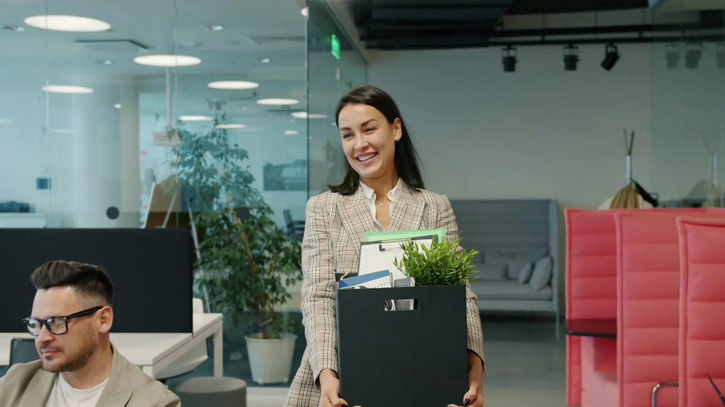 Empleada que deja la oficina con una caja de pertenencias