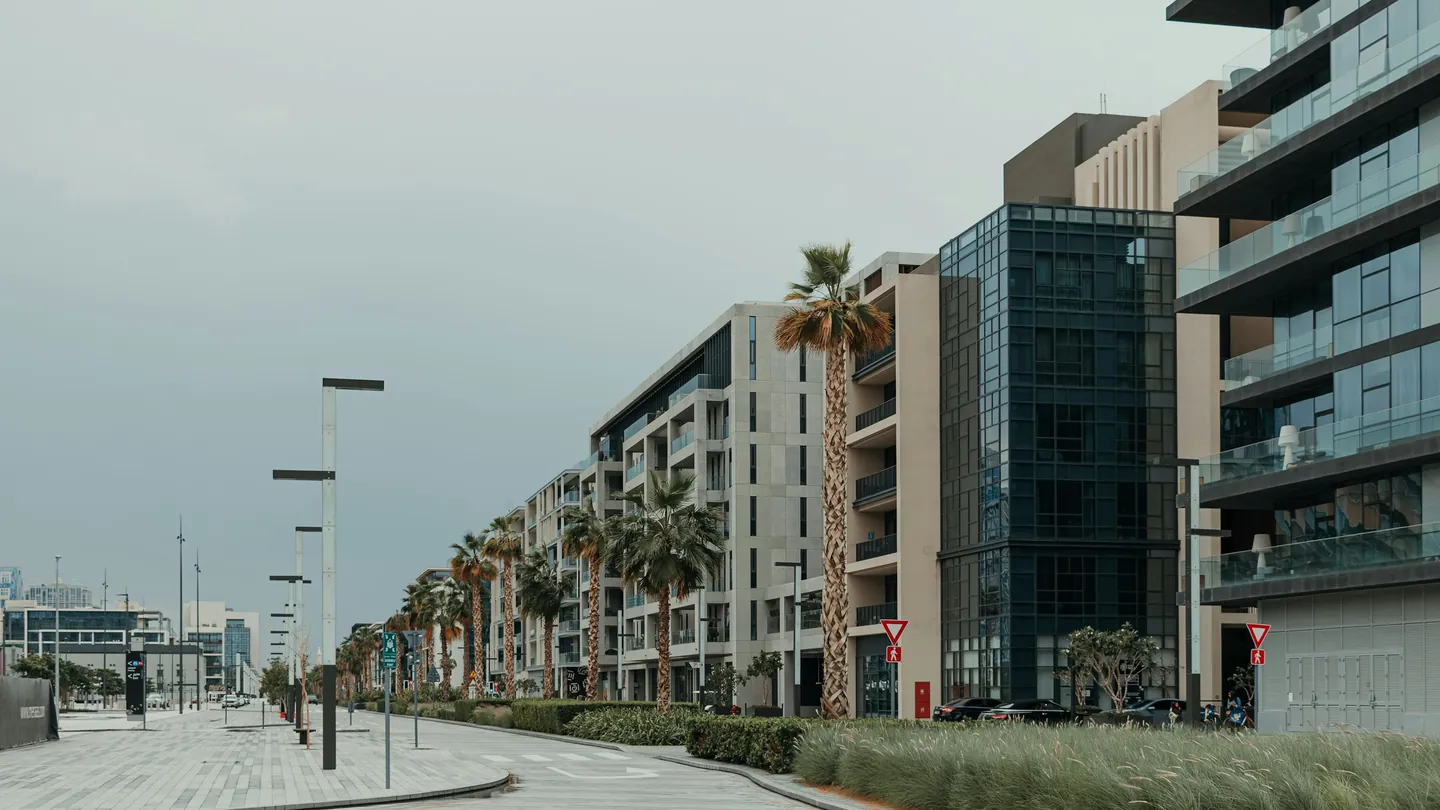 Modern residential buildings along a quiet palm-lined street in Dubai