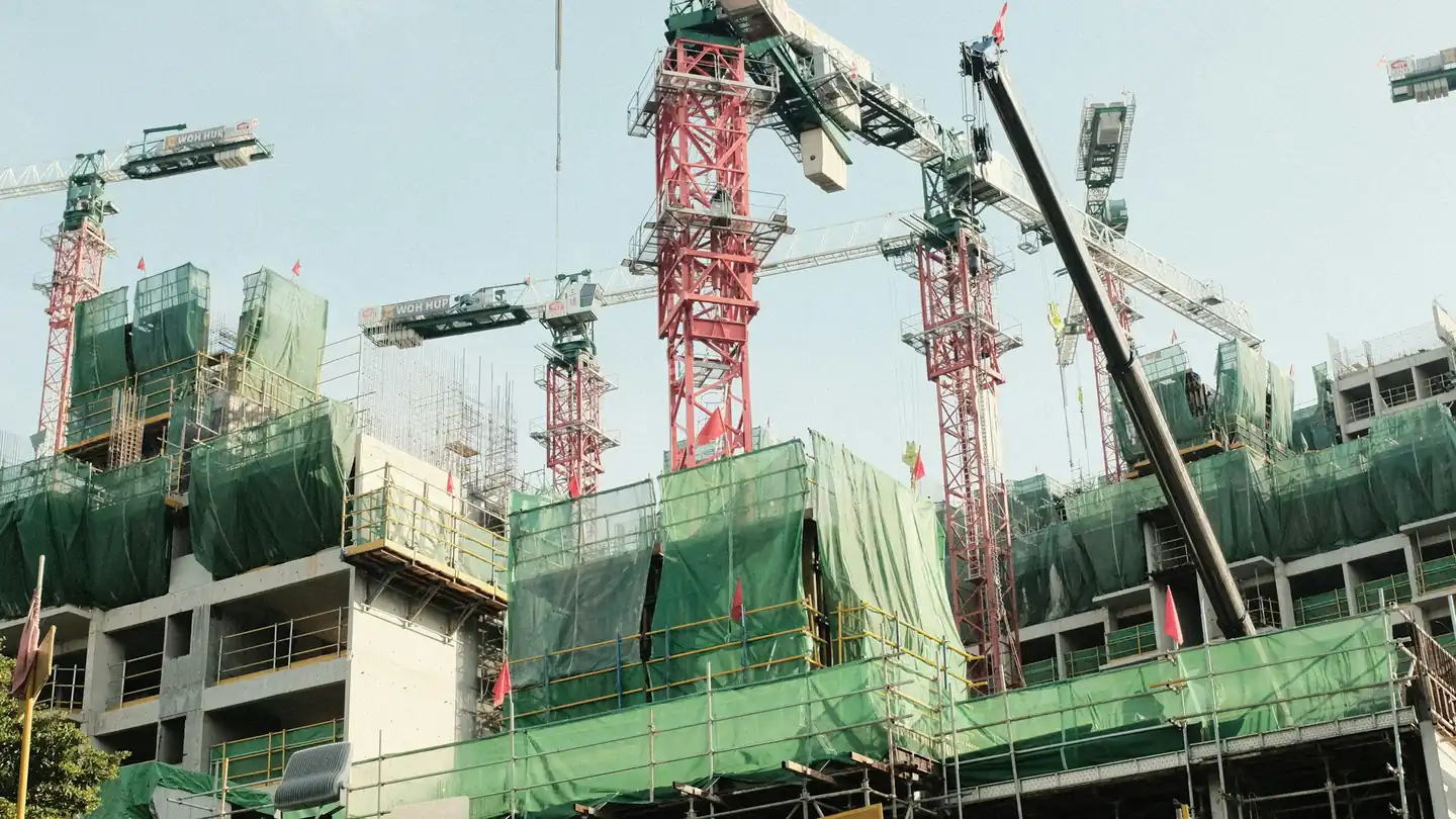 Construction site with tower cranes and green scaffolding nets