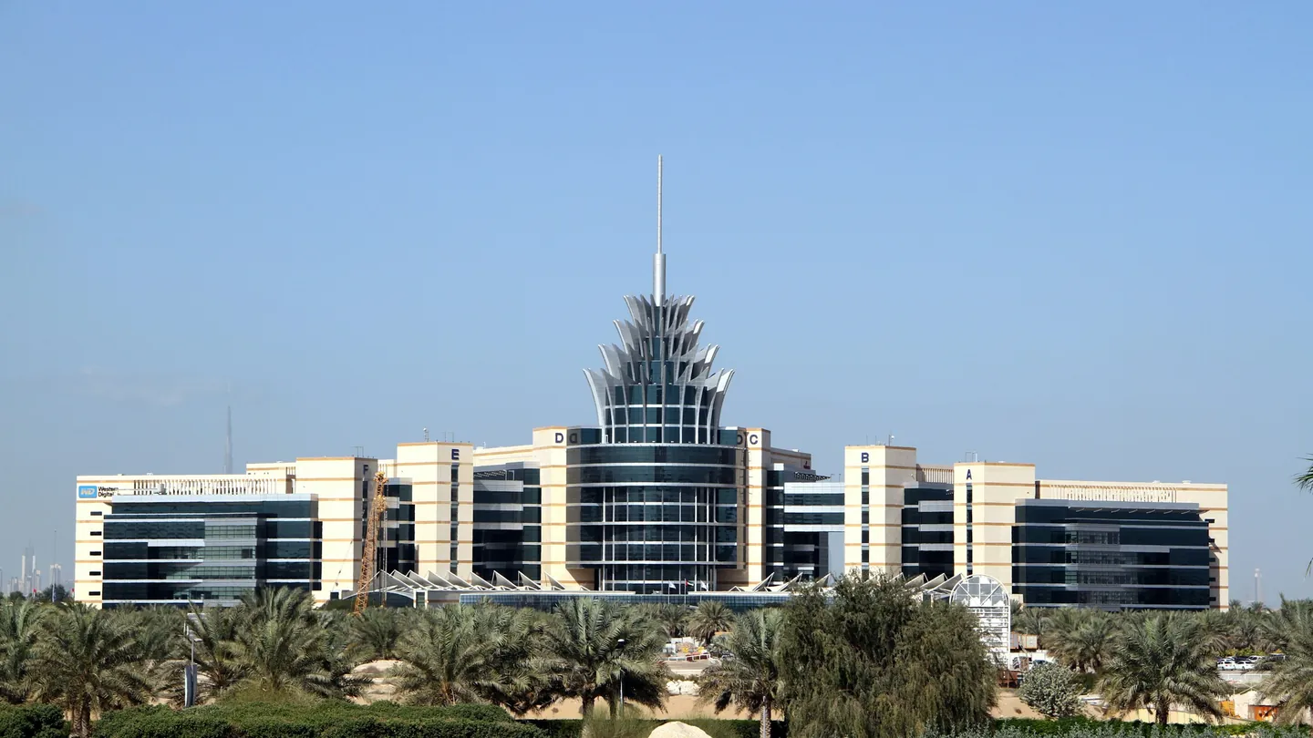The Dubai Silicon Oasis headquarters building with its spire behind palm trees